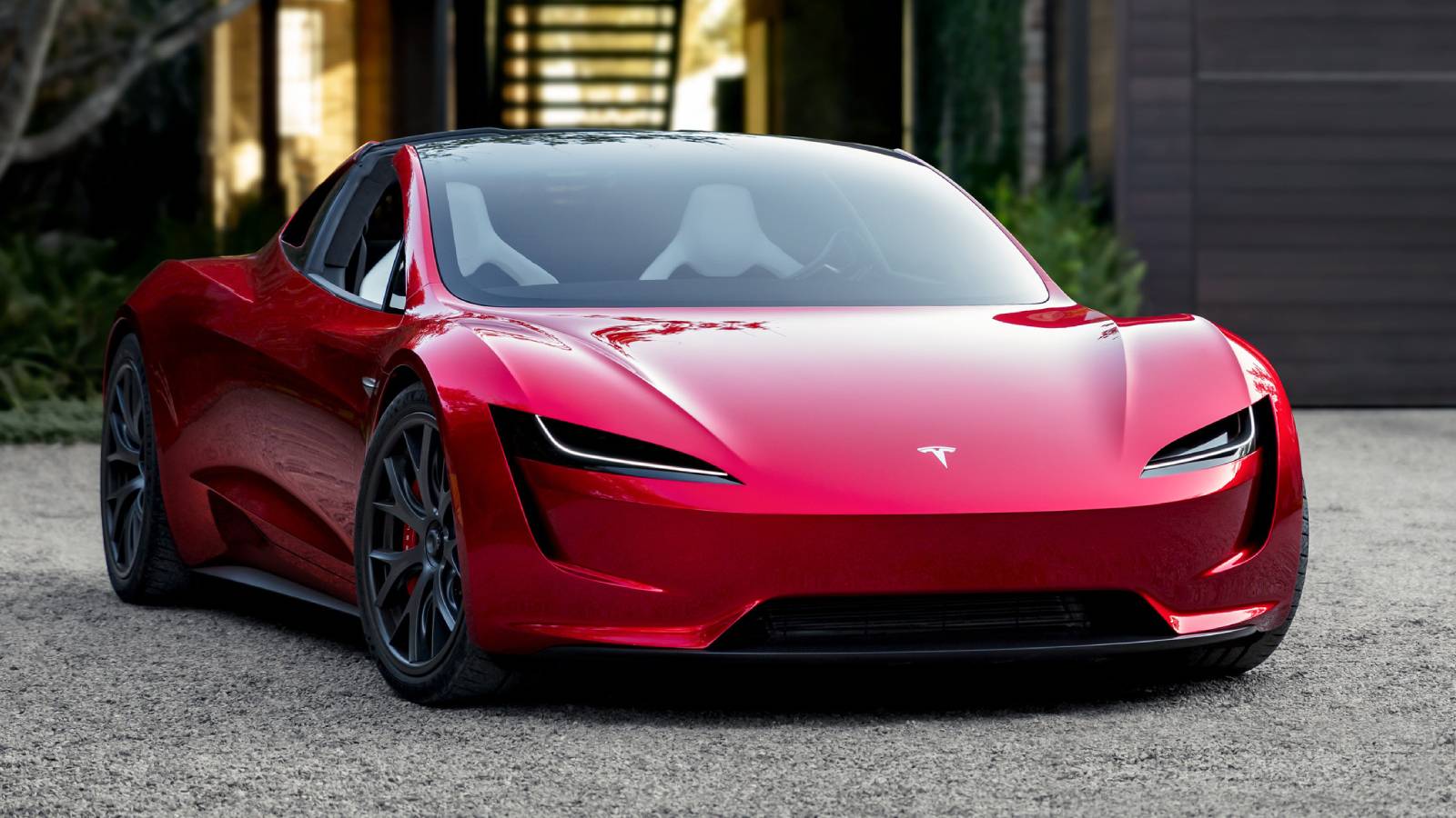 Красный Tesla Roadster у современного дома