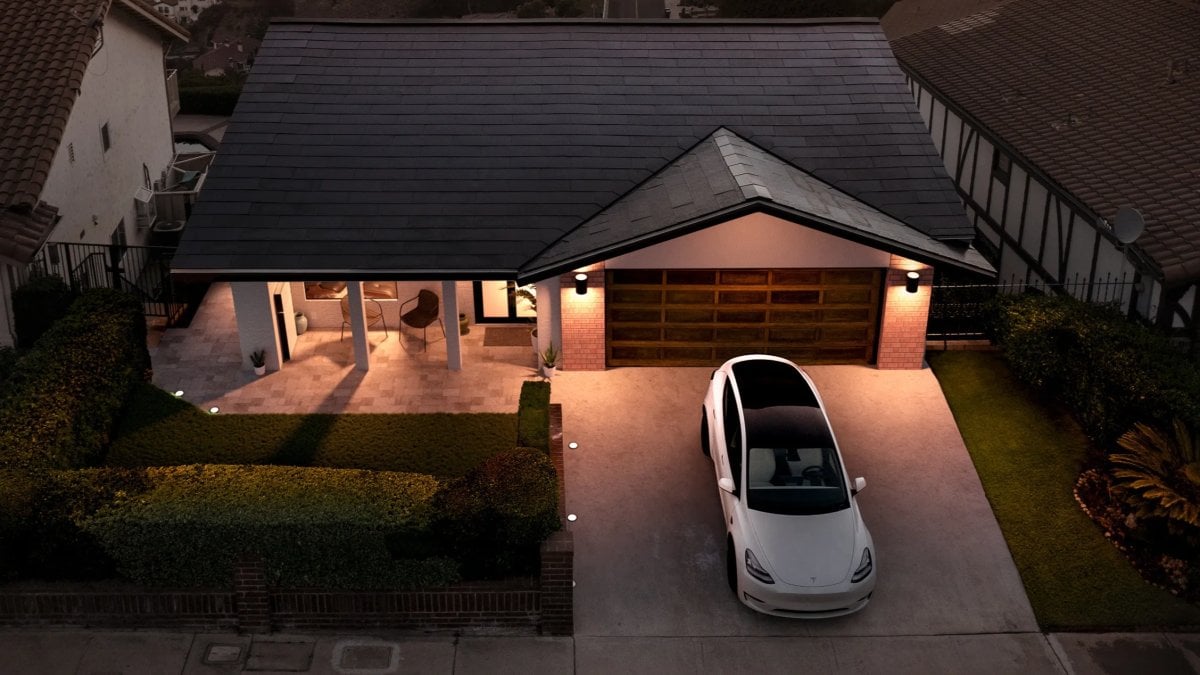 Дом с солнечной крышей Tesla Solar Roof и электромобилем в подъездной дорожке